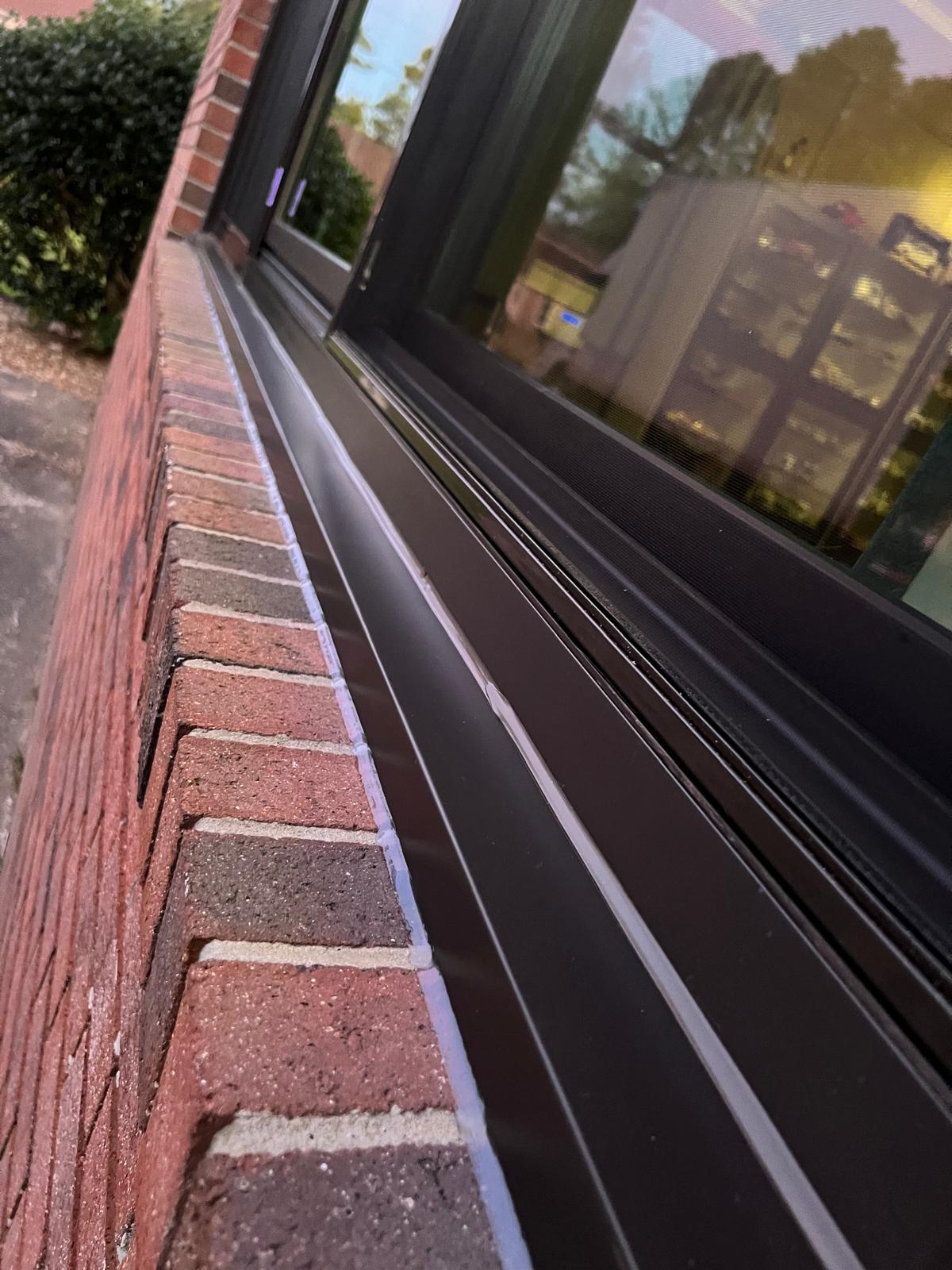 Close-up detail of a new black-framed window and sill installed on a brick home in Fuquay-Varina, NC
