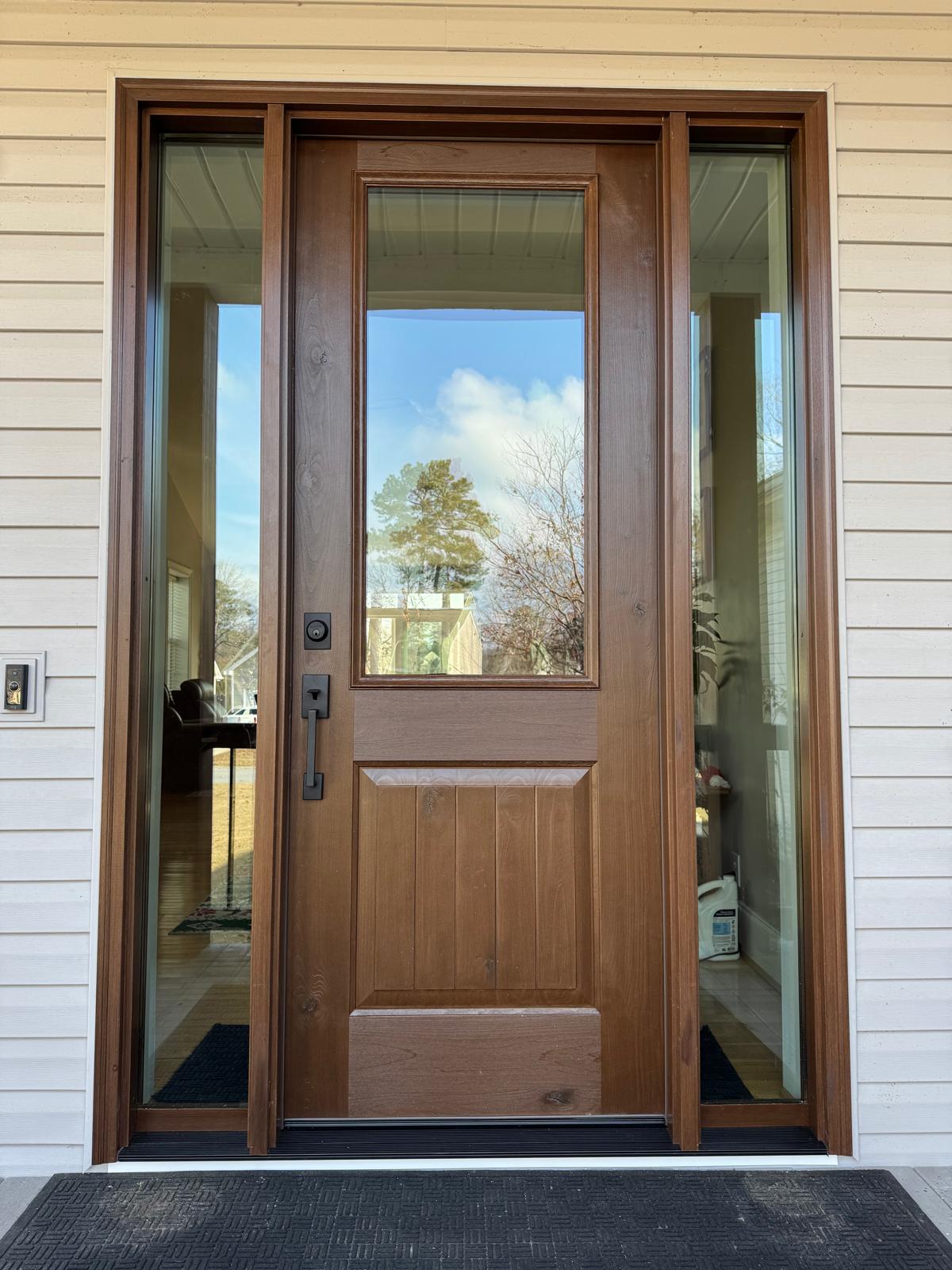 Stained wood front door with sidelites installed on a home
