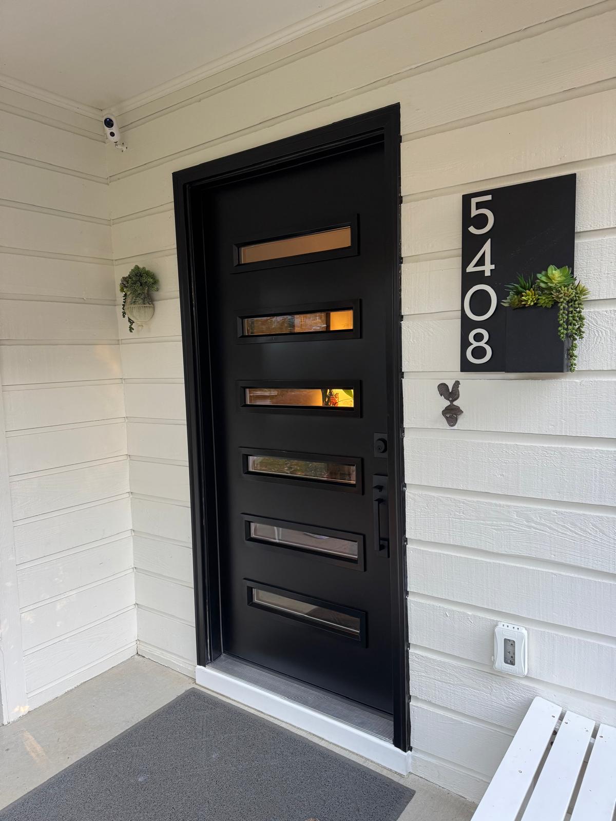 Modern black entry door with glass inserts installed on a home